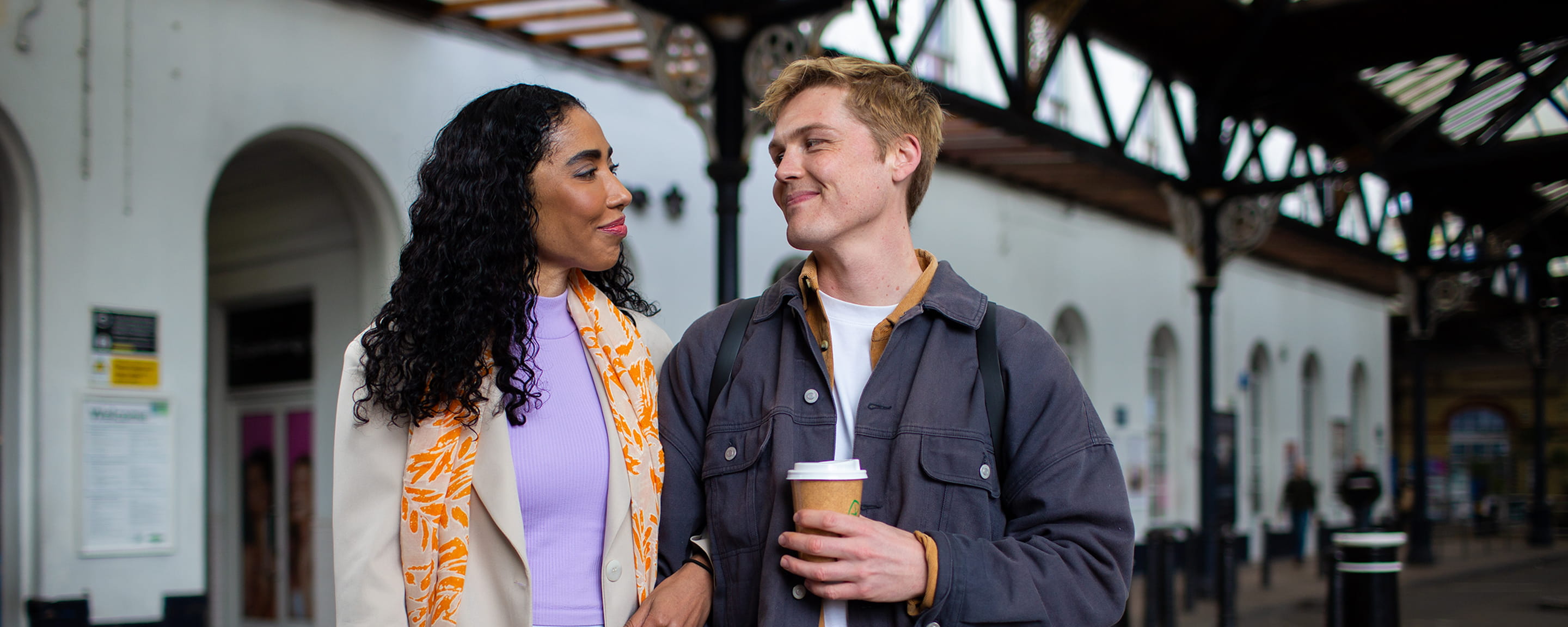 A woman and a man smiling at each other at a railway station