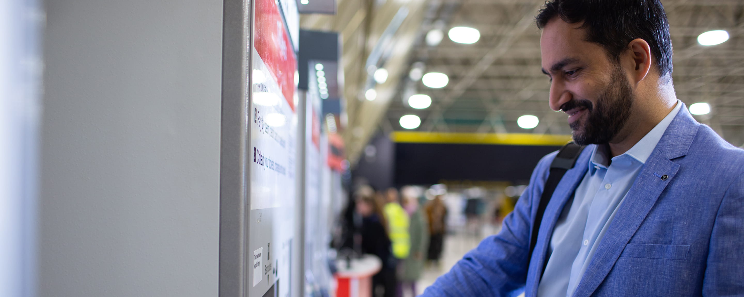 A man using a ticket vending machine at a railway station