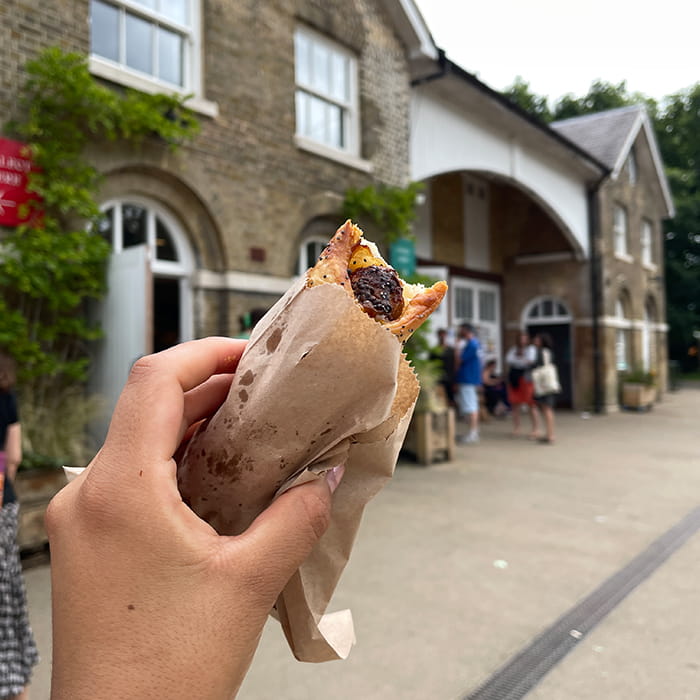 Closeup of a hand holding food in front of a cafe