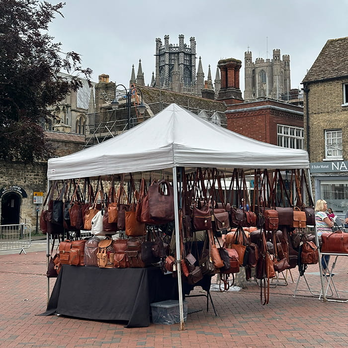 A market stall of leather bags with a castle and buildings in the background