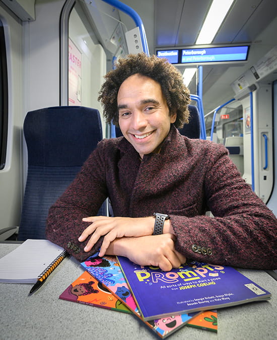 A man sitting in a train carriage at a table with books