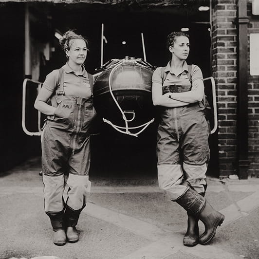 Old black and white photo of two women standing by a lifeboat
