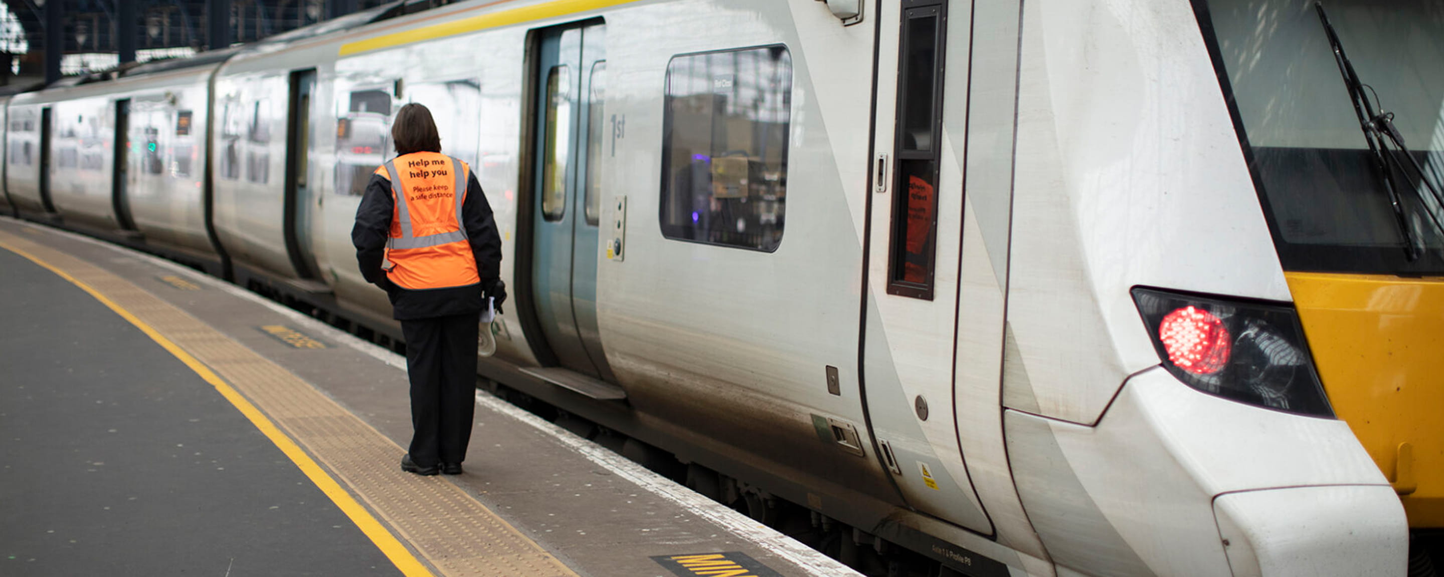 A staff member standing on a train platform next to a train