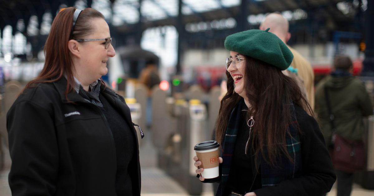 woman laughing with thameslink staff in railway station