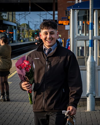 A man holding flowers on a railway platform